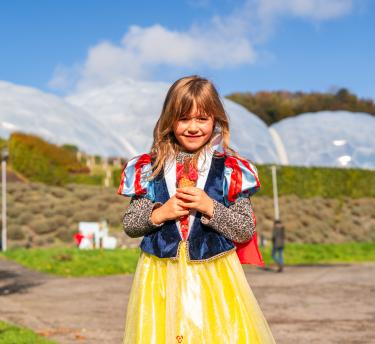Girl wearing fancy dress stood in front of Eden Project Biome